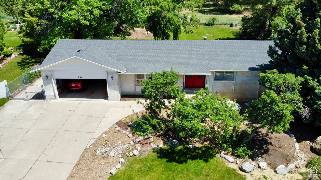 View of front of home with a garage, a gate, brick siding, driveway, and roof with shingles