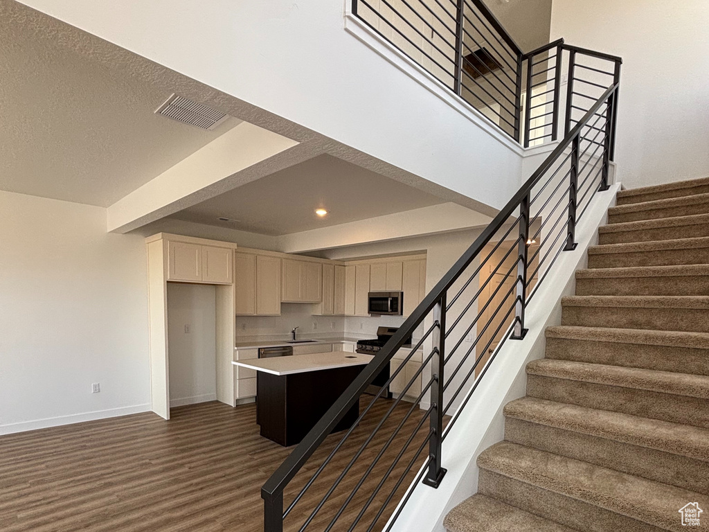 Stairway featuring wood finished floors, baseboards, recessed lighting, and a high ceiling