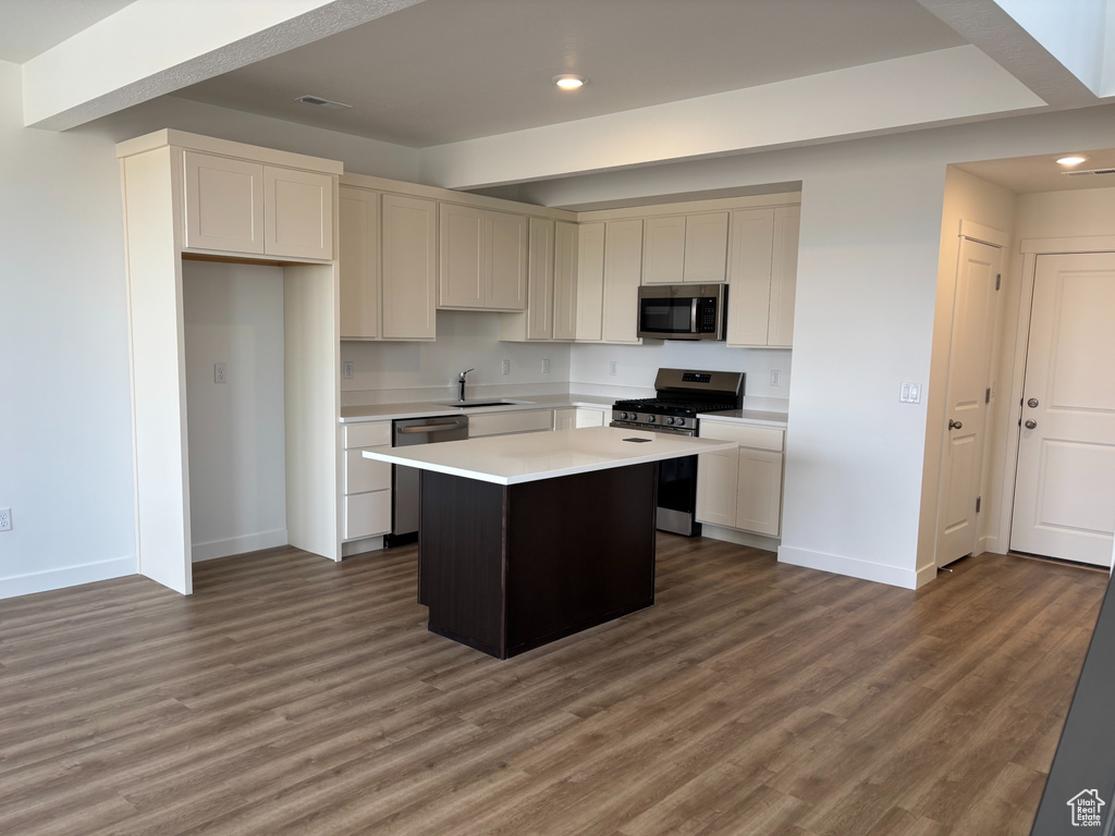 Kitchen with appliances with stainless steel finishes, baseboards, recessed lighting, light countertops, and a center island