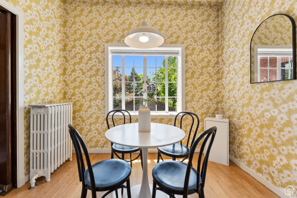 Dining area with radiator, light wood-type flooring, wallpapered walls, and baseboards