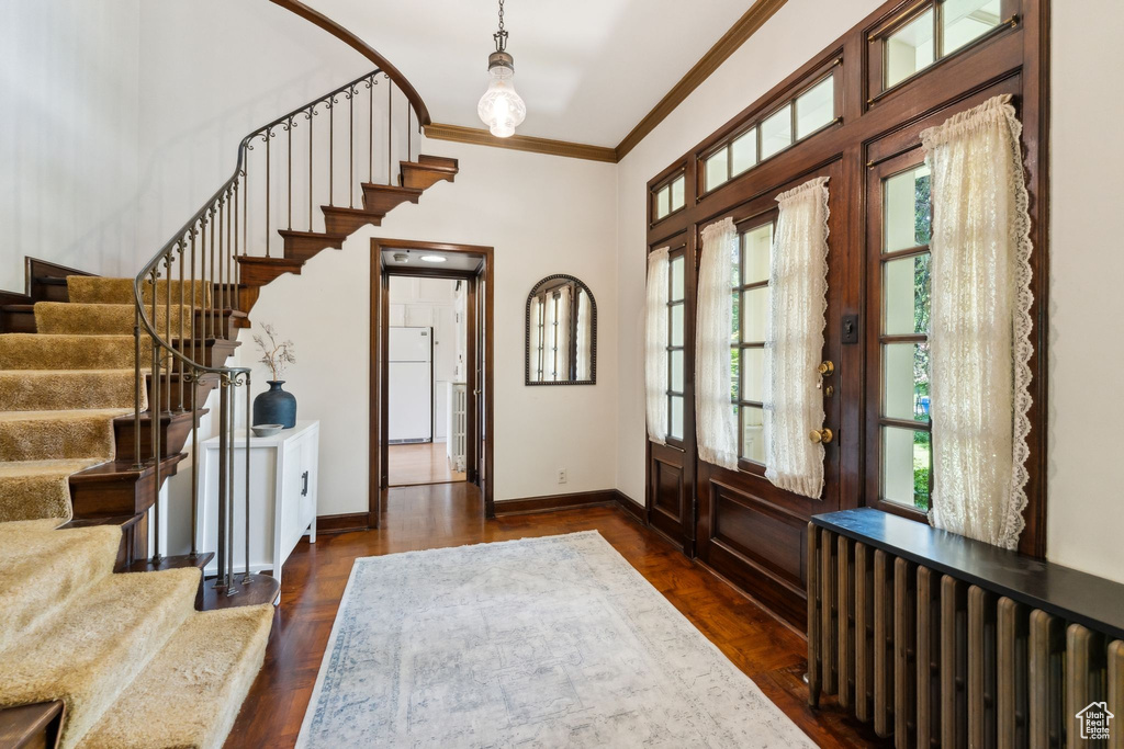 Foyer featuring ornamental molding, stairs, baseboards, and a towering ceiling