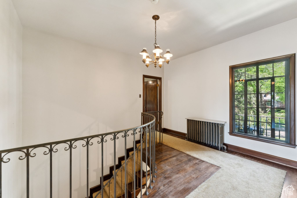 Staircase featuring a chandelier, wood finished floors, baseboards, and radiator heating unit