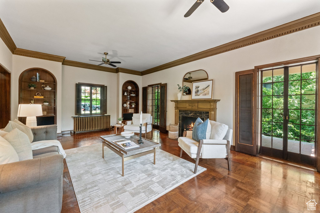 Living area with a ceiling fan, radiator heating unit, ornamental molding, and healthy amount of natural light