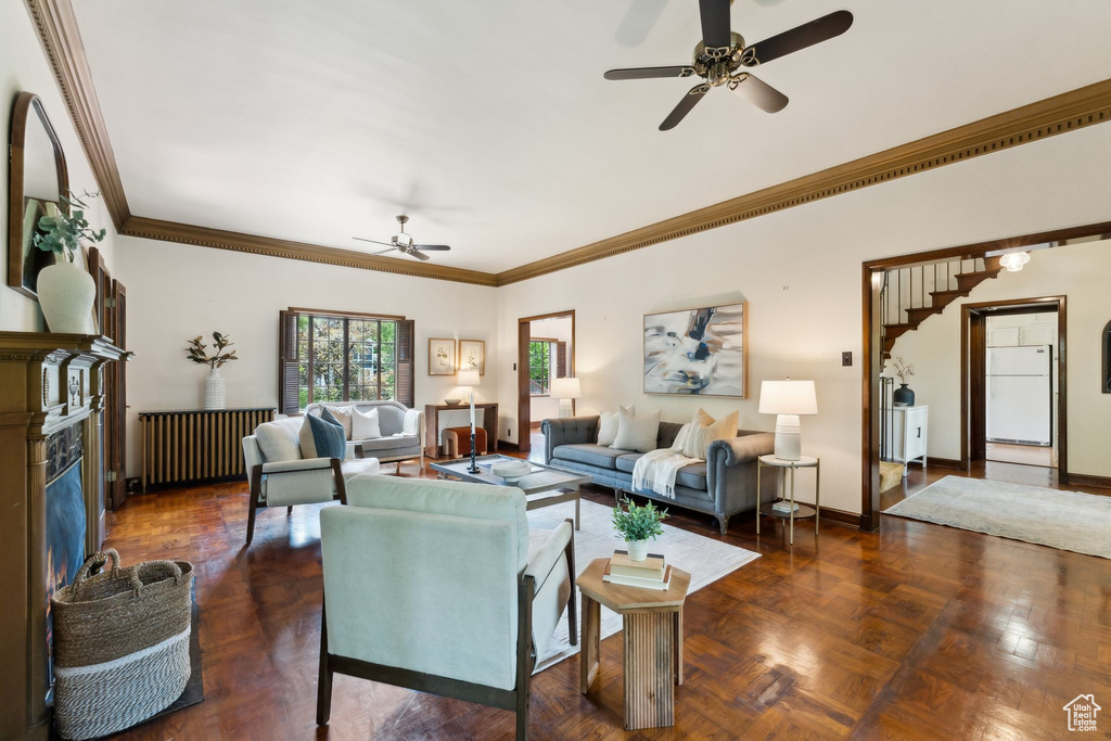 Living room featuring a ceiling fan, ornamental molding, a premium fireplace, and baseboards