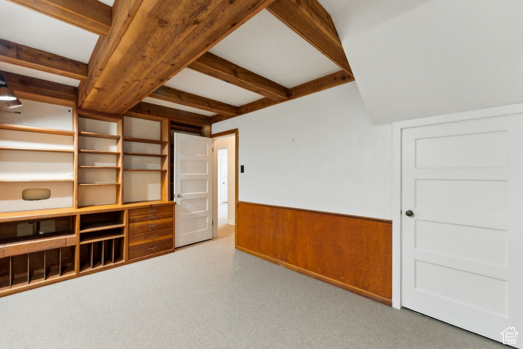 Empty room featuring a wainscoted wall, beam ceiling, and wooden walls