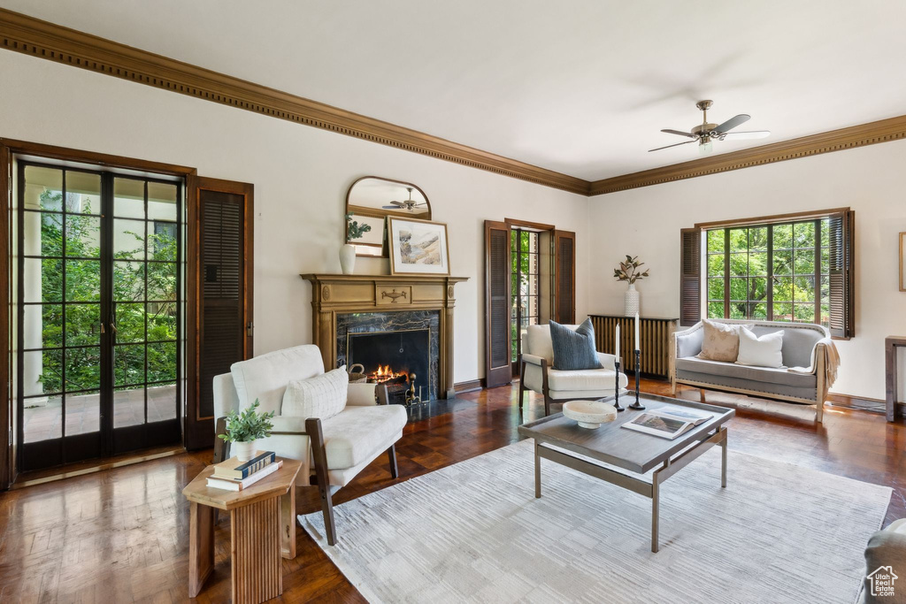 Living area featuring healthy amount of natural light, crown molding, a fireplace, ceiling fan, and baseboards