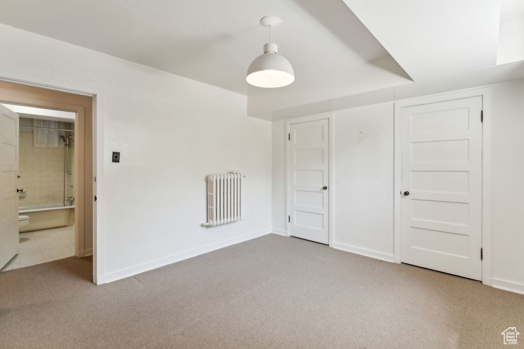 Unfurnished bedroom featuring radiator, carpet floors, baseboards, and a closet