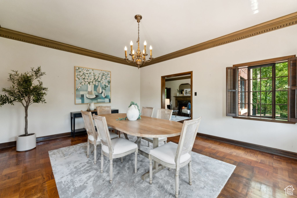 Dining area with a chandelier, baseboards, and crown molding