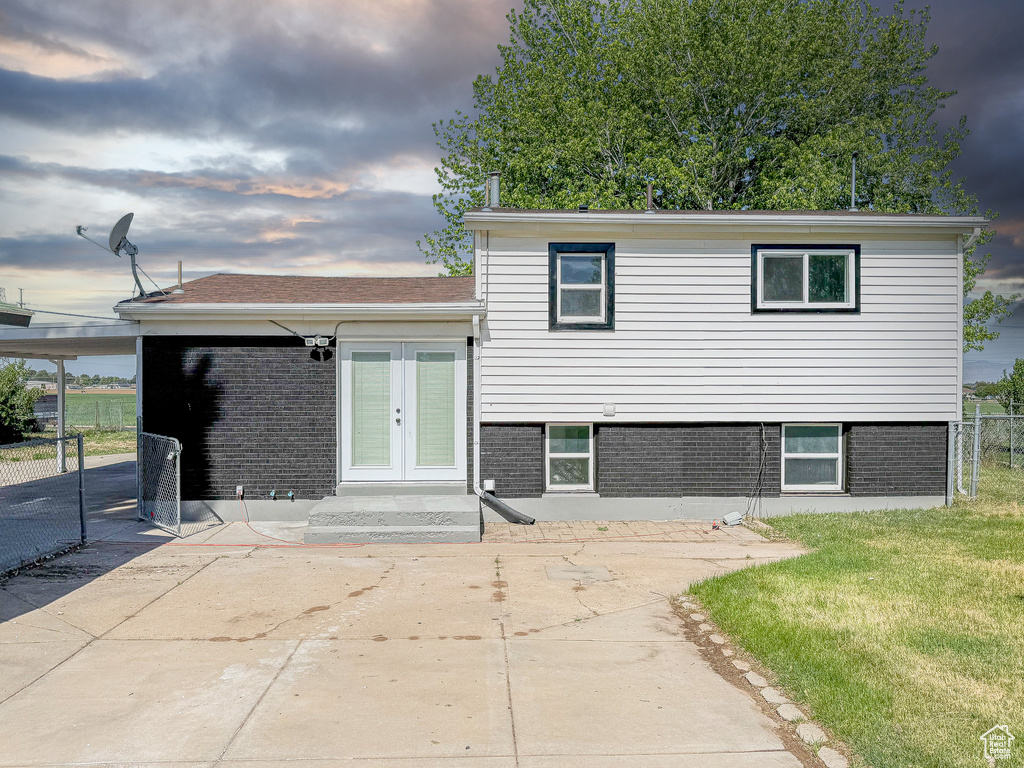 Split level home featuring french doors, brick siding, and a patio