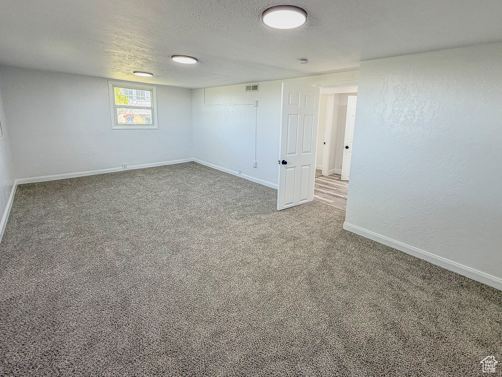 Spare room featuring carpet flooring, baseboards, and a textured ceiling