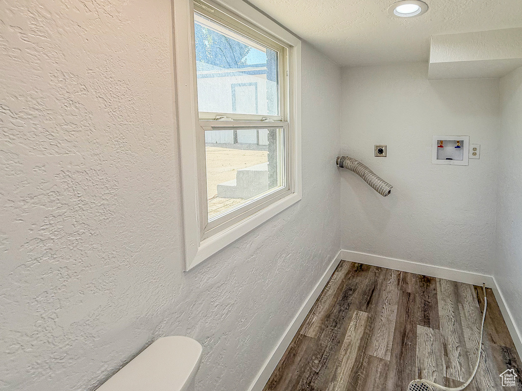 Laundry area with hookup for an electric dryer, baseboards, dark wood-style flooring, hookup for a washing machine, and a textured ceiling