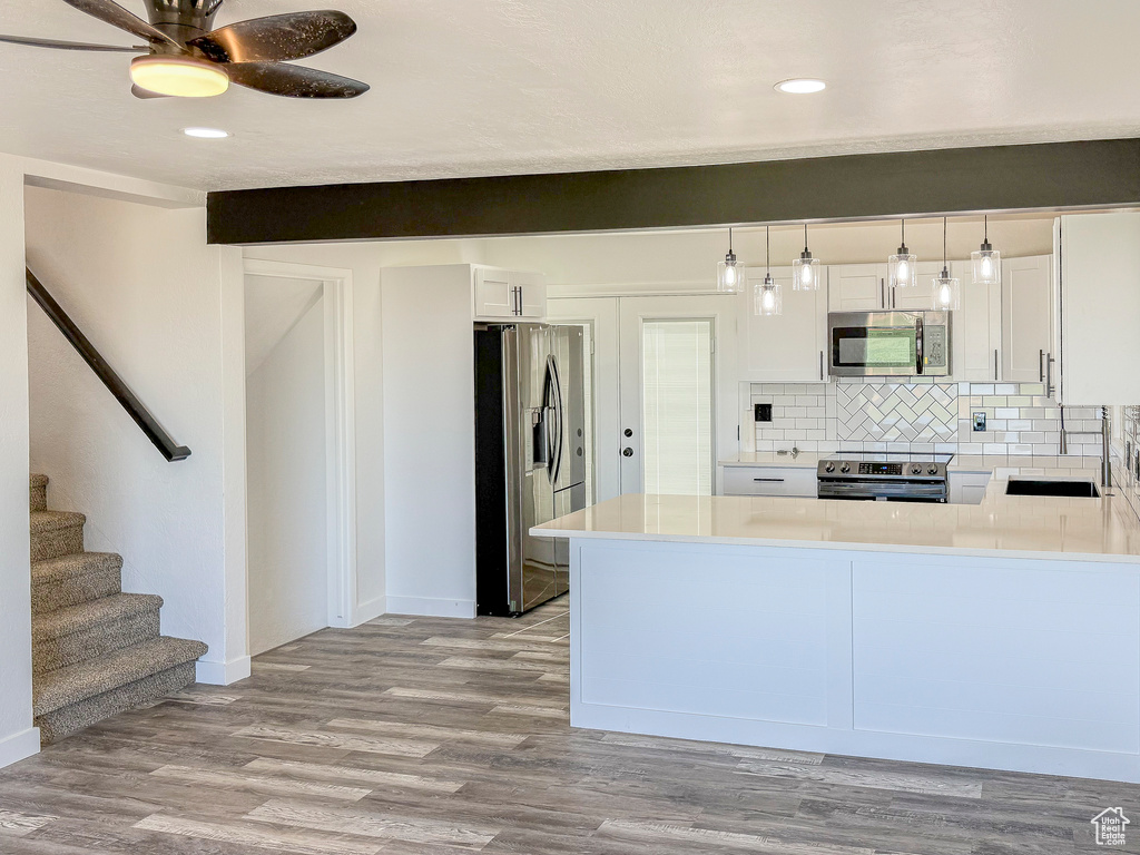 Kitchen featuring stainless steel appliances, tasteful backsplash, light wood finished floors, white cabinets, and recessed lighting