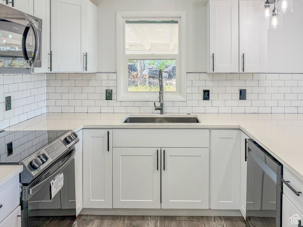 Kitchen with stainless steel appliances, a sink, backsplash, and light countertops