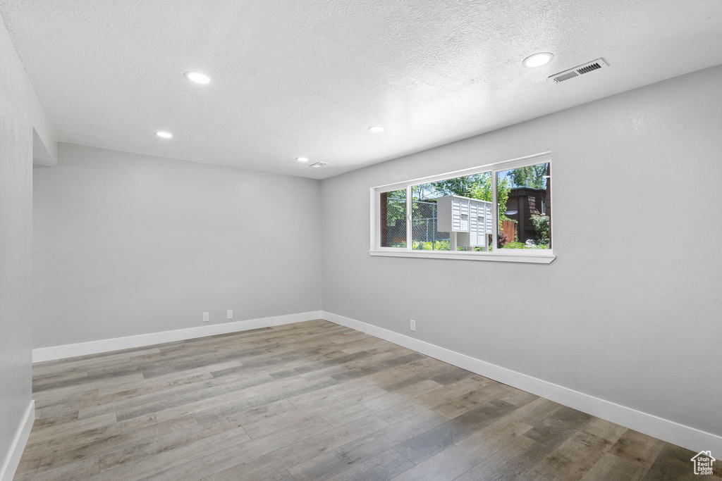 Spare room featuring baseboards, recessed lighting, wood finished floors, and a textured ceiling