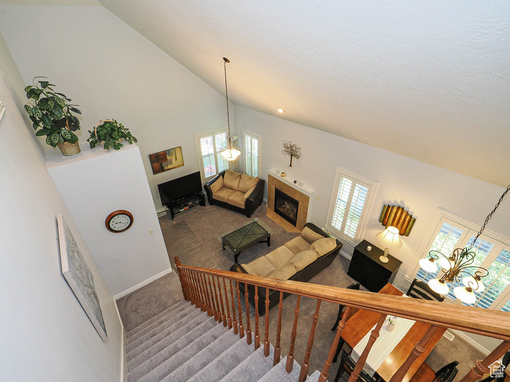 Stairs featuring carpet flooring, a tiled fireplace, vaulted ceiling, and baseboards