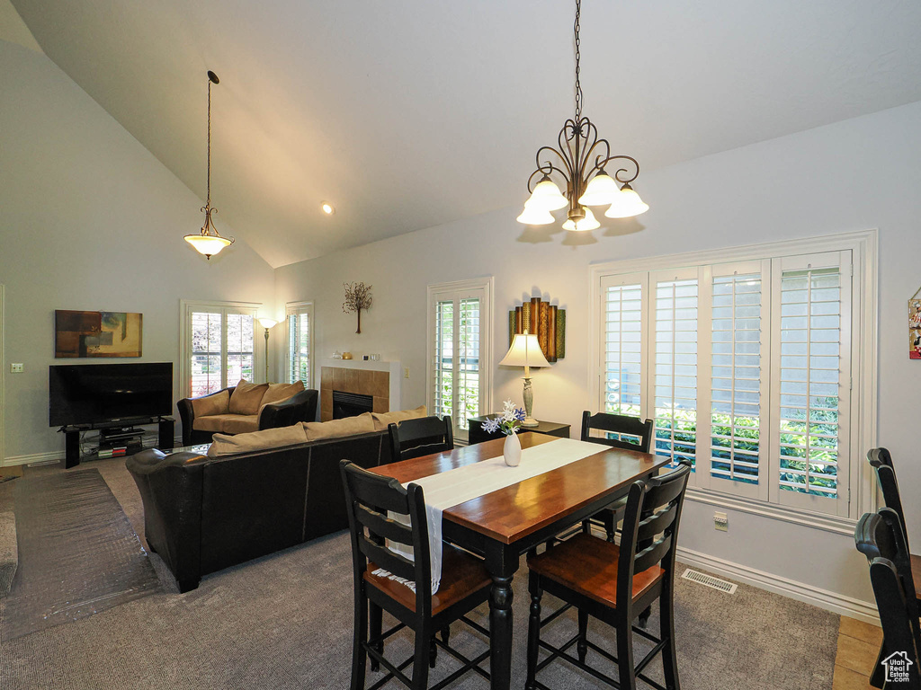 Dining space featuring a chandelier, baseboards, a tile fireplace, high vaulted ceiling, and recessed lighting