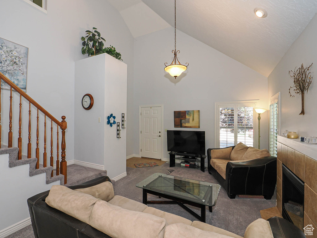 Carpeted living room featuring high vaulted ceiling, stairway, and baseboards
