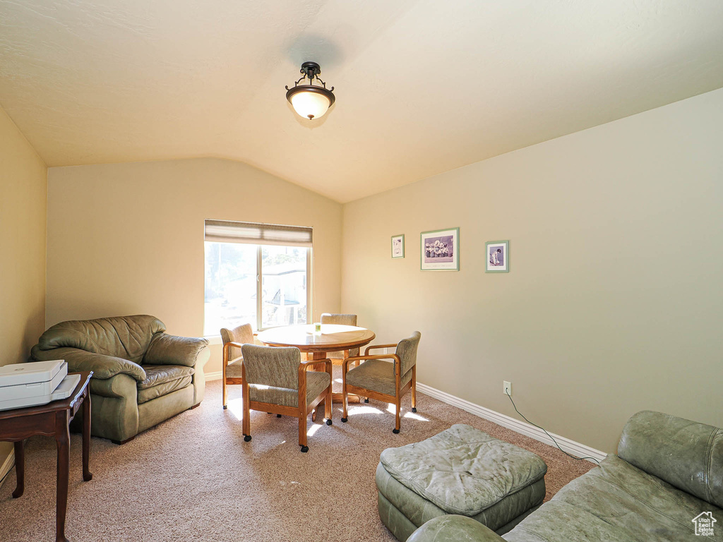Dining space with light colored carpet, vaulted ceiling, and baseboards