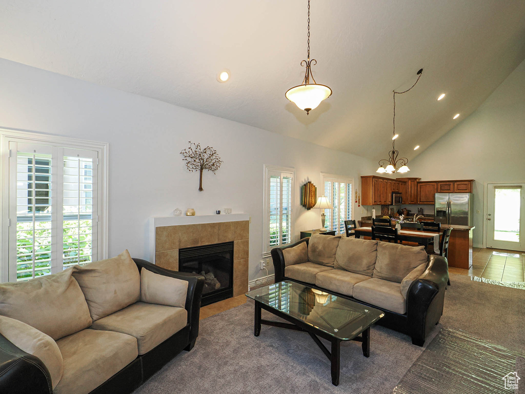 Living room featuring plenty of natural light, a fireplace, recessed lighting, high vaulted ceiling, and a chandelier