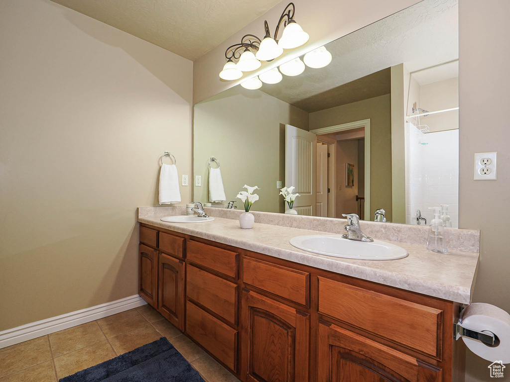 Full bath with double vanity, tile patterned flooring, and baseboards