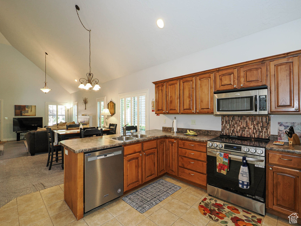 Kitchen with stainless steel appliances, a sink, dark countertops, open floor plan, and a chandelier