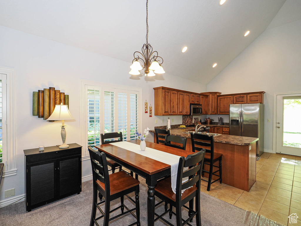 Dining room with a chandelier, recessed lighting, high vaulted ceiling, light tile patterned floors, and baseboards