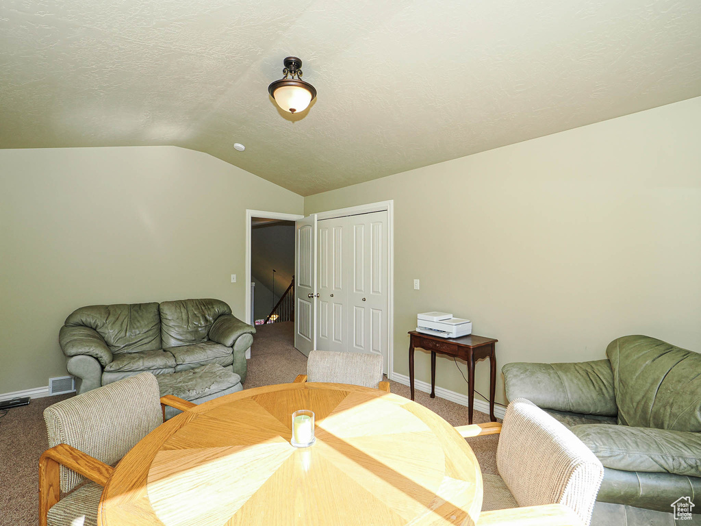 Dining room with lofted ceiling, carpet flooring, and baseboards
