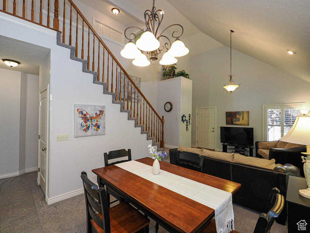 Carpeted dining space featuring high vaulted ceiling, stairs, a chandelier, and baseboards