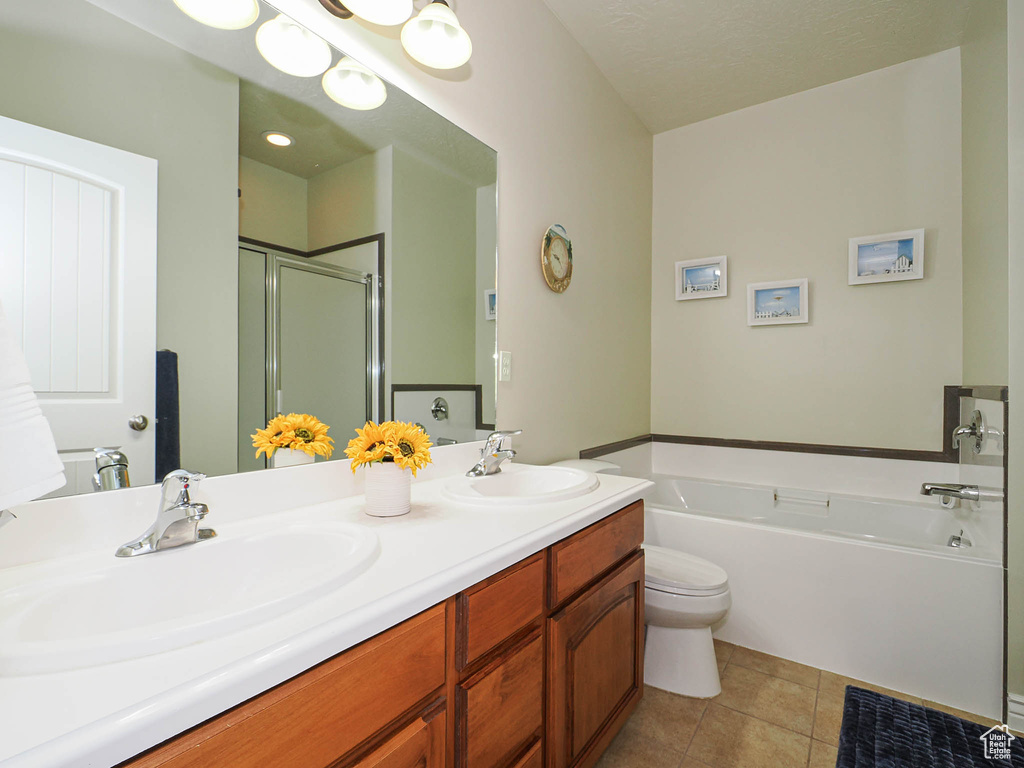 Full bathroom featuring a bath, a stall shower, double vanity, toilet, and tile patterned flooring