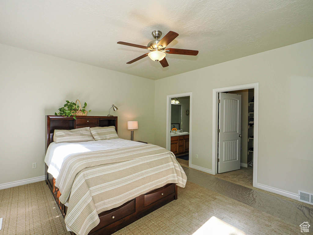Bedroom featuring light colored carpet, baseboards, and ensuite bath