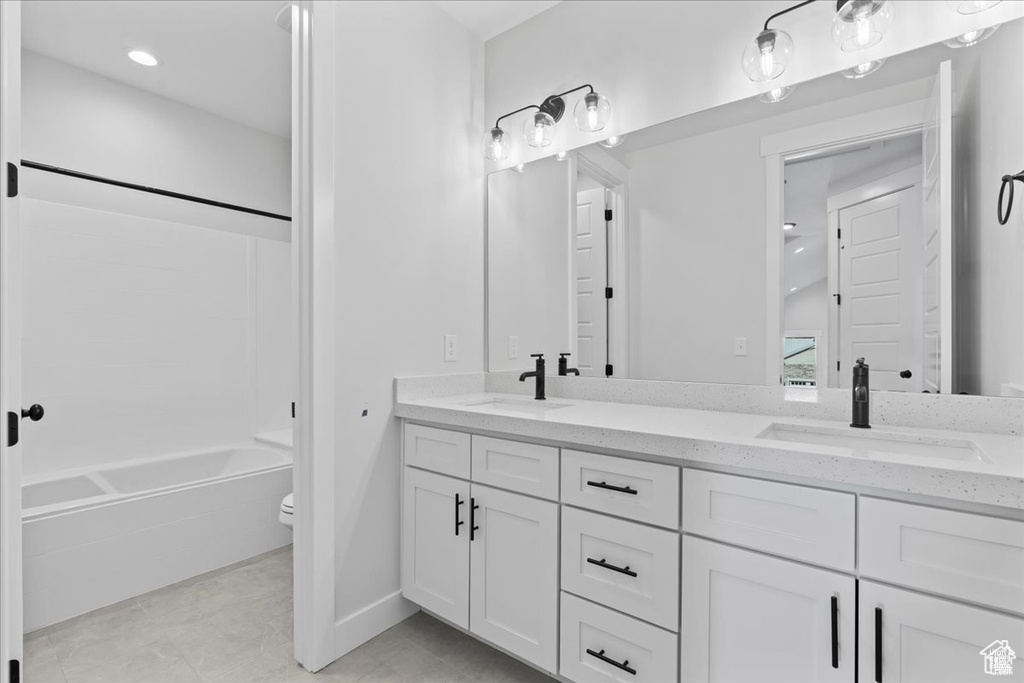 Bathroom featuring double vanity, toilet, bathtub / shower combination, baseboards, and tile patterned floors