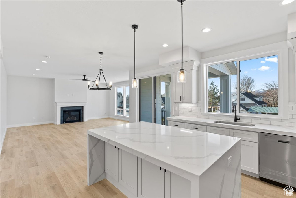 Kitchen featuring dishwasher, a sink, a center island, backsplash, and recessed lighting