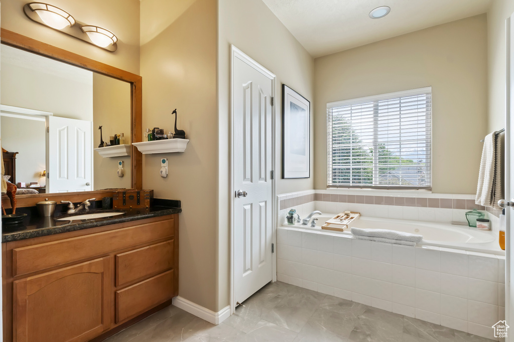 Full bathroom featuring a bath, vanity, marble finish floors, and baseboards