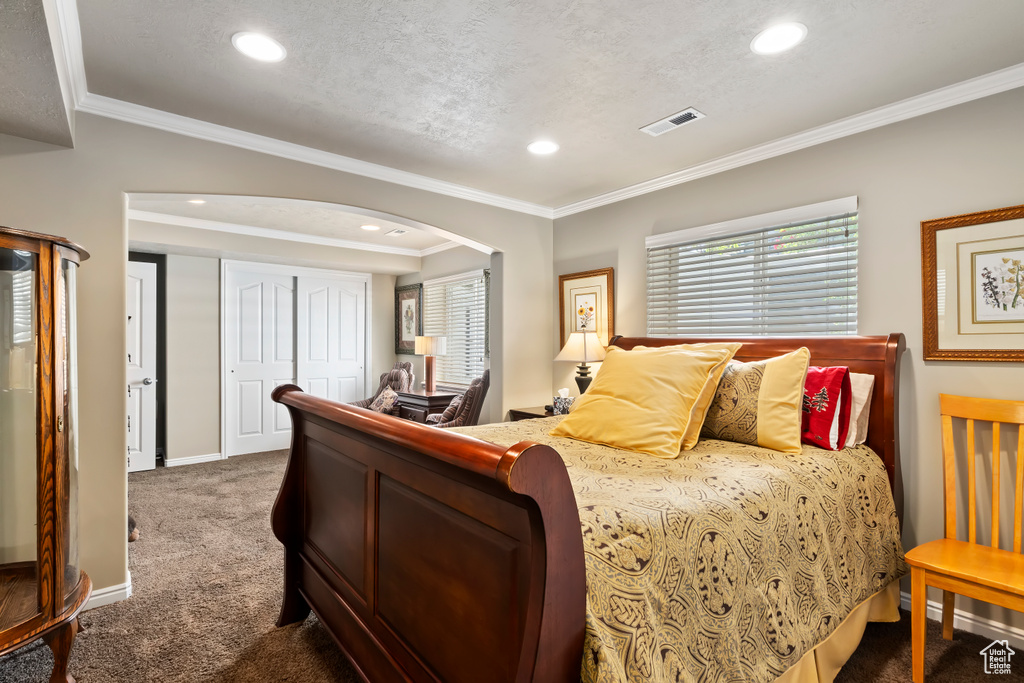 Carpeted bedroom featuring arched walkways, recessed lighting, ornamental molding, and baseboards