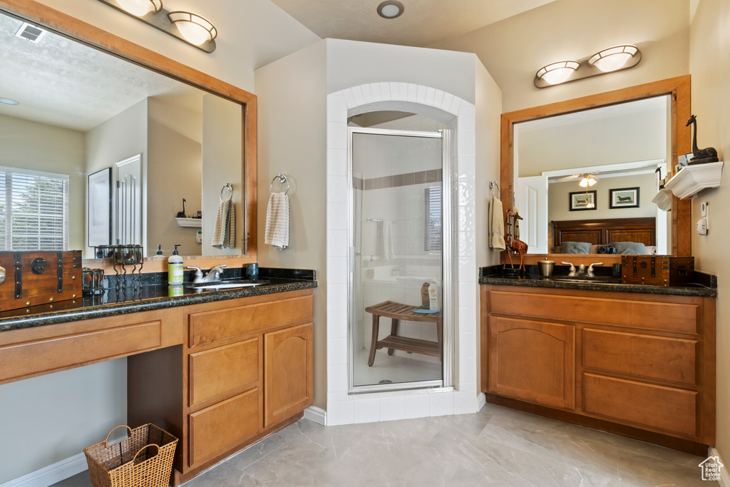 Full bathroom with a shower stall, marble look tiles, and vanity
