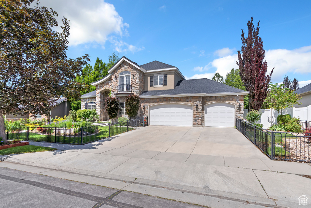 Traditional home featuring stone siding, concrete driveway, a garage, and a shingled roof