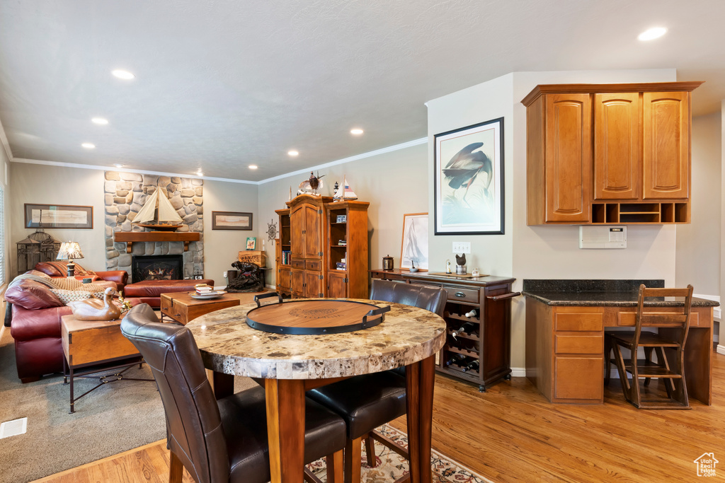 Dining room featuring light wood-style floors, a fireplace, recessed lighting, crown molding, and an office area