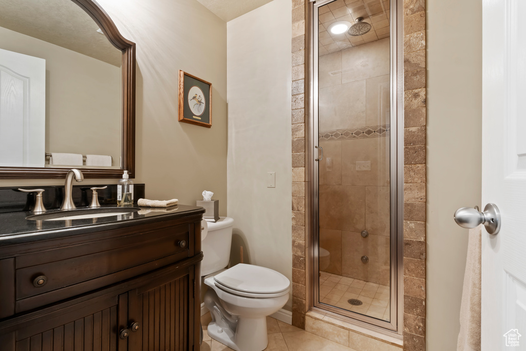 Full bathroom with toilet, vanity, a stall shower, and tile patterned floors