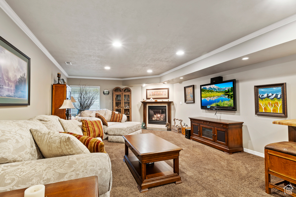 Carpeted living area featuring recessed lighting, a glass covered fireplace, baseboards, and ornamental molding