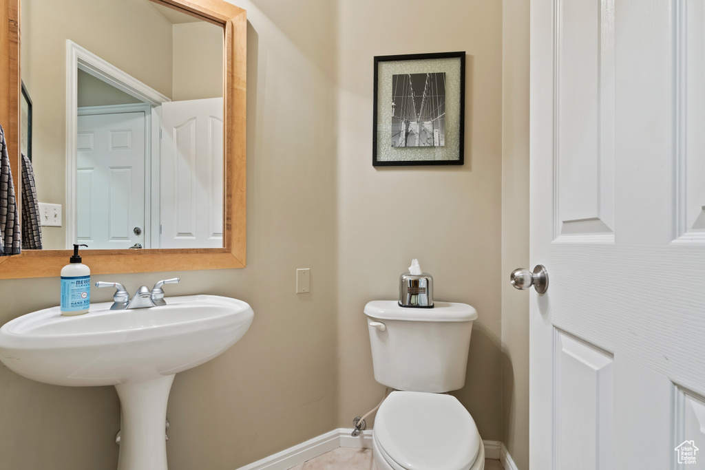 Half bathroom featuring baseboards, toilet, and a sink