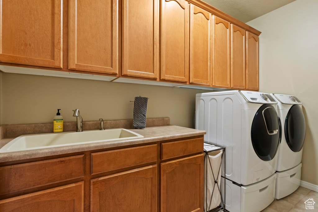 Laundry room with washing machine and dryer, cabinet space, and light tile patterned floors