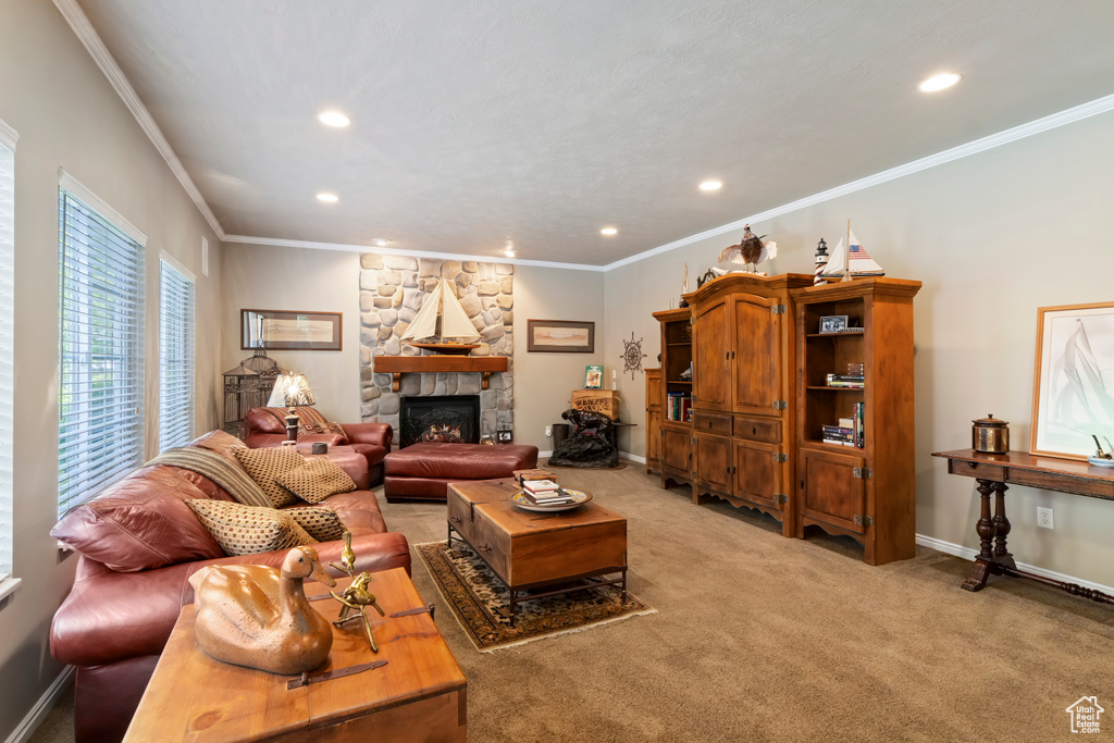 Living area featuring recessed lighting, ornamental molding, a stone fireplace, baseboards, and light carpet