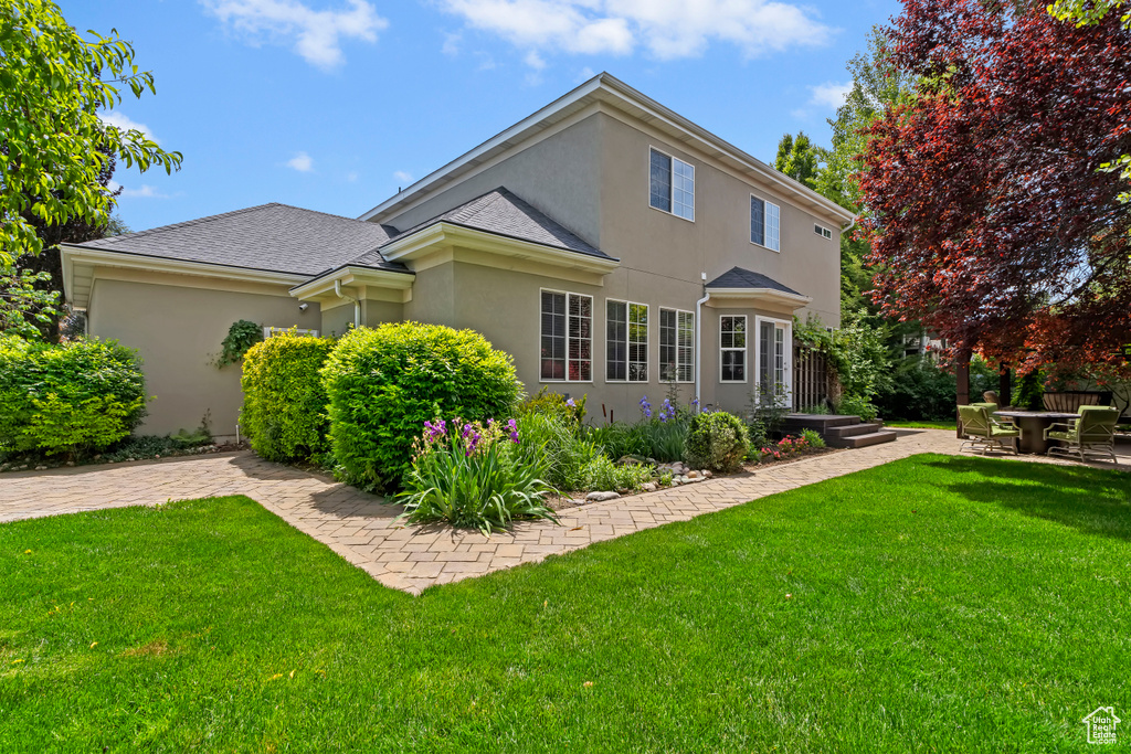 Back of property featuring stucco siding and a lawn