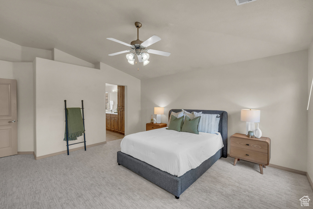 Bedroom featuring lofted ceiling, baseboards, a ceiling fan, ensuite bath, and light carpet