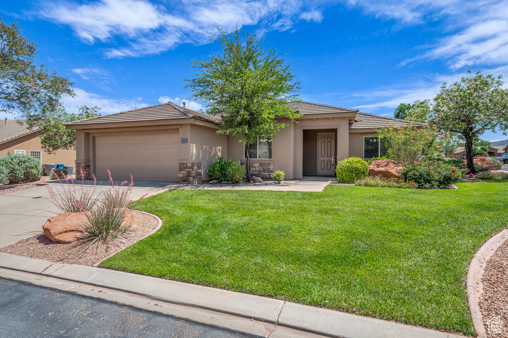 View of front of house featuring stucco siding, driveway, a garage, and a front lawn