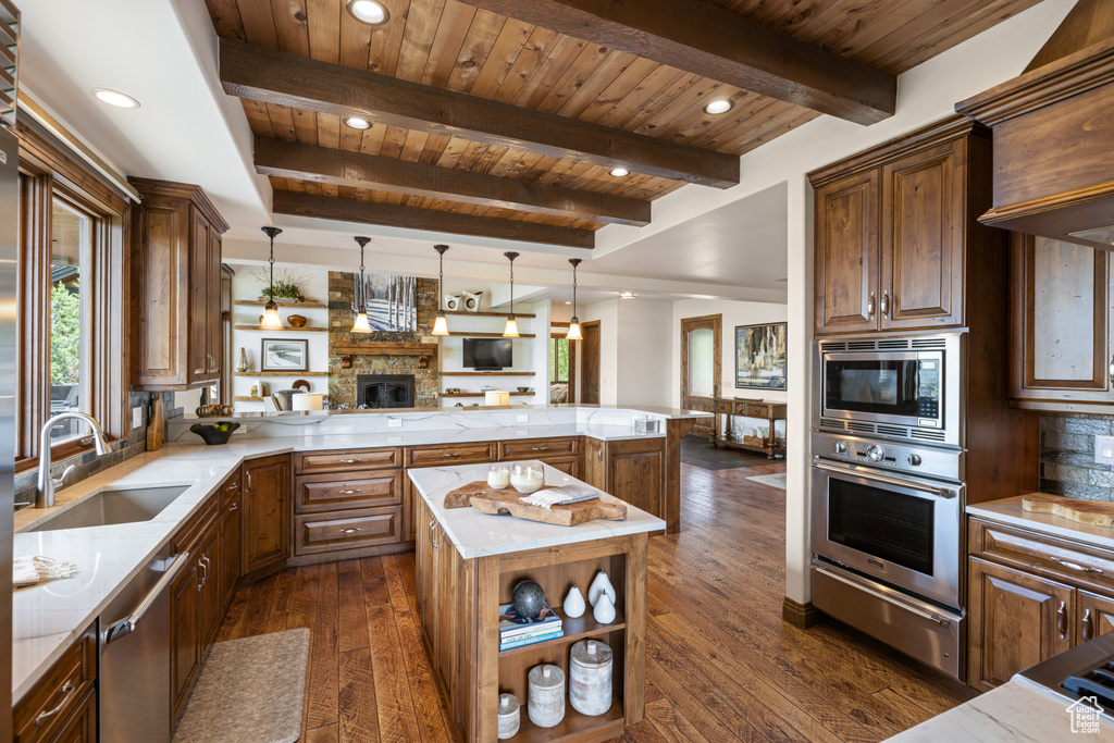 Kitchen with appliances with stainless steel finishes, open floor plan, a warming drawer, a sink, and dark wood-type flooring
