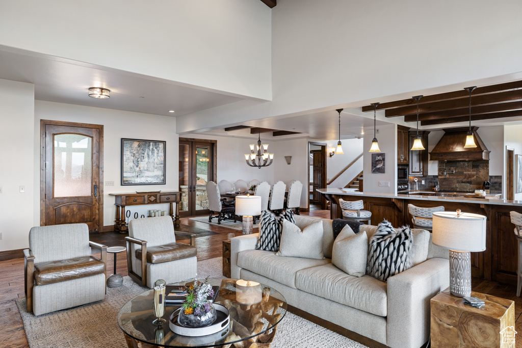 Living room featuring a chandelier, plenty of natural light, wood finished floors, stairs, and beam ceiling
