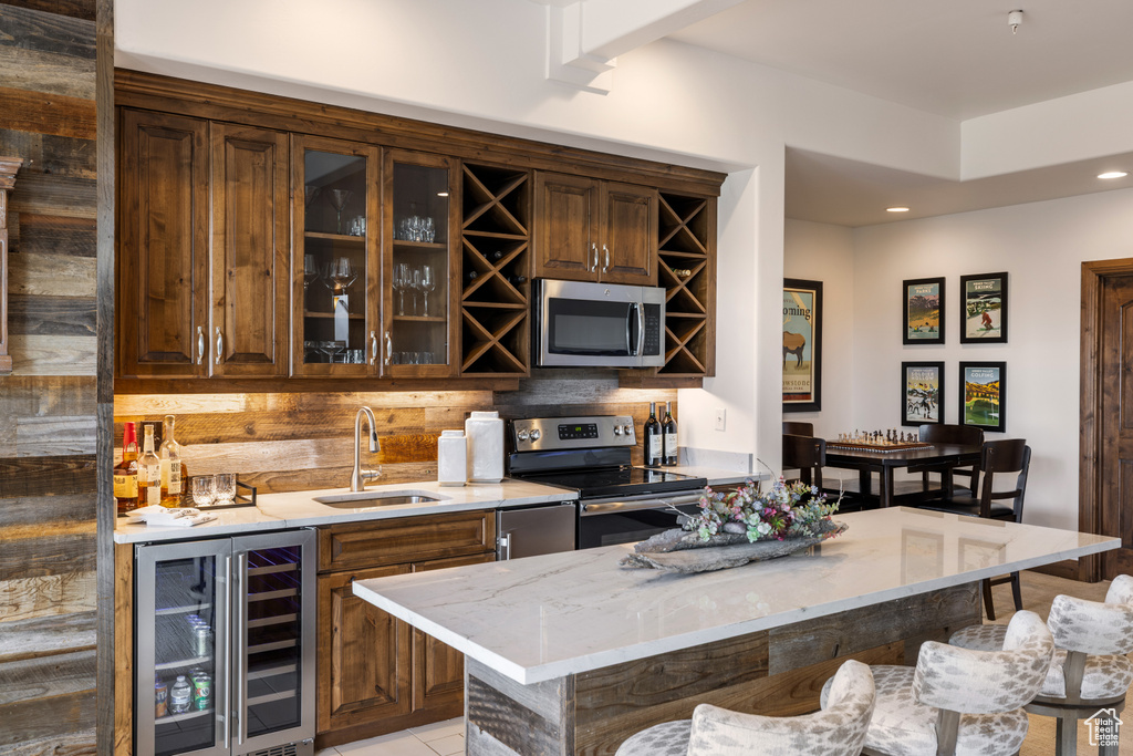 Indoor wet bar with stainless steel appliances, wine cooler, decorative backsplash, and recessed lighting