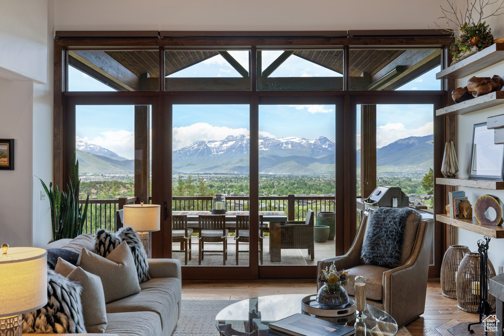 Living room featuring healthy amount of natural light, a mountain view, wood finished floors, expansive windows, and lofted ceiling