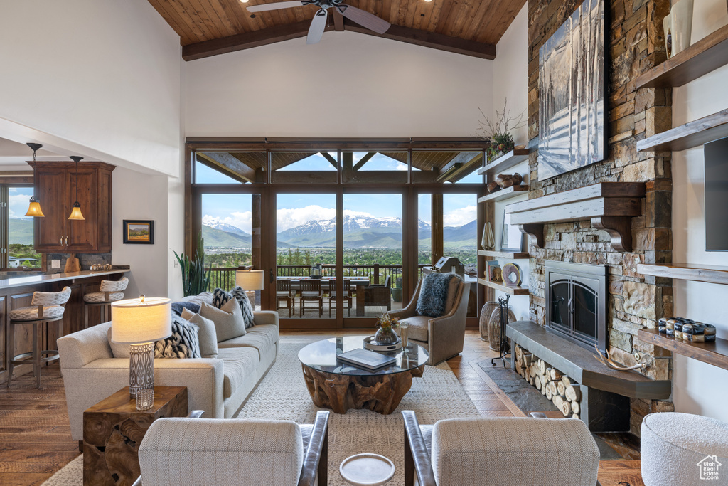 Living area featuring high vaulted ceiling, a mountain view, a ceiling fan, wooden ceiling, and a stone fireplace